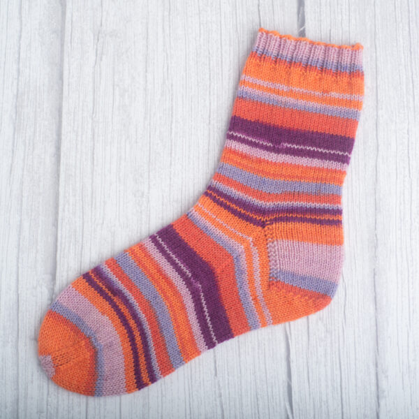 Ohuesta, oranssin ja lilan sävyisestä sukkalangasta neulottu sukka